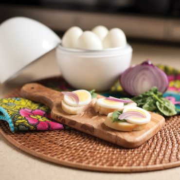 Sliced hard boiled eggs on cutting board with onion and basil  garnish